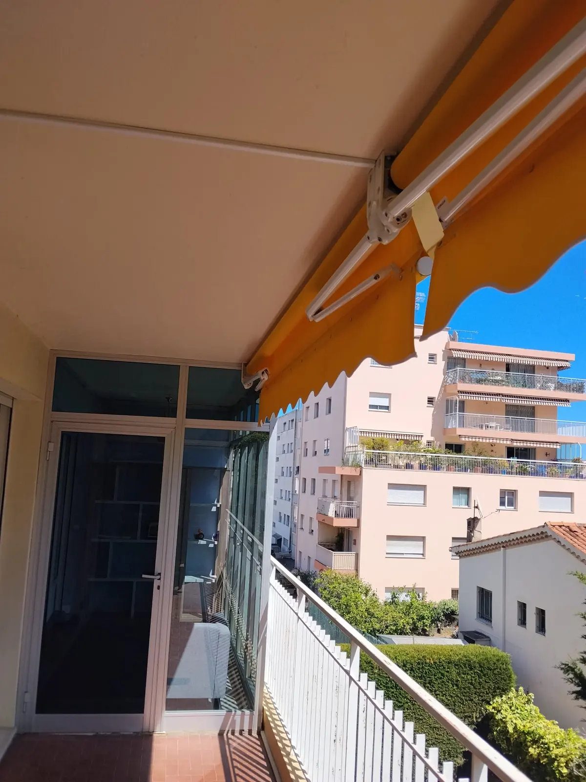 Store banne à rayures orange et brunes installé sur un balcon.